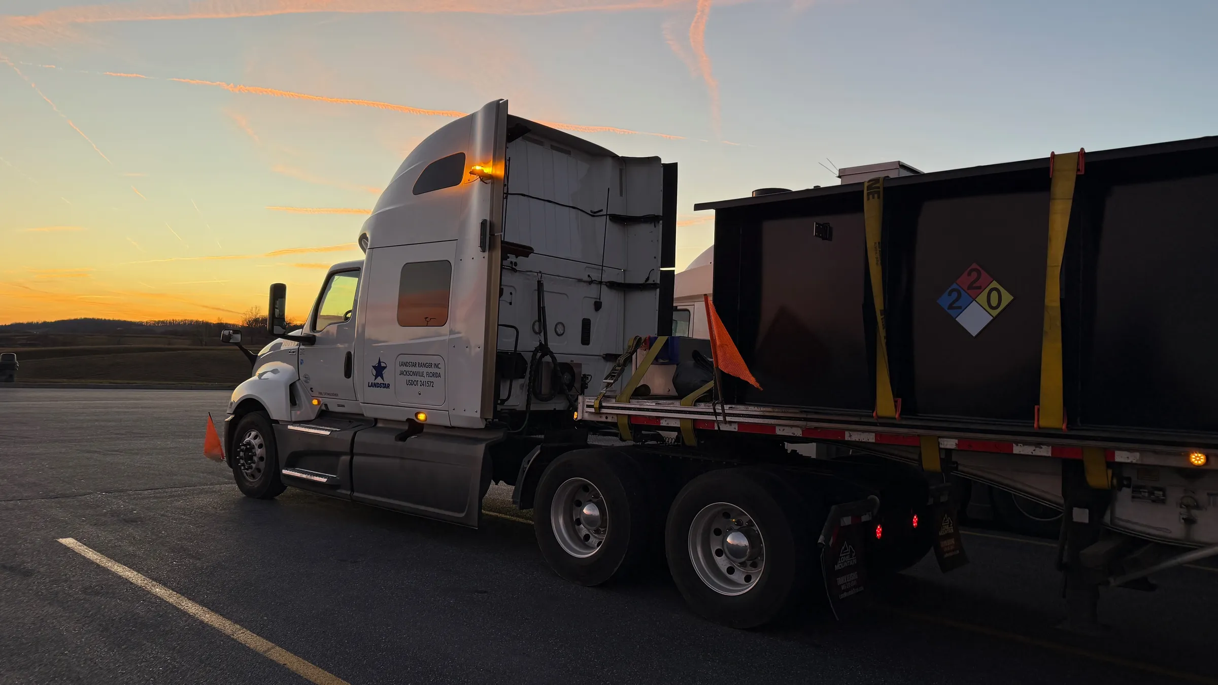 Delgado Trucking Services unit 580991 — Landstar flatbed loaded at sunset